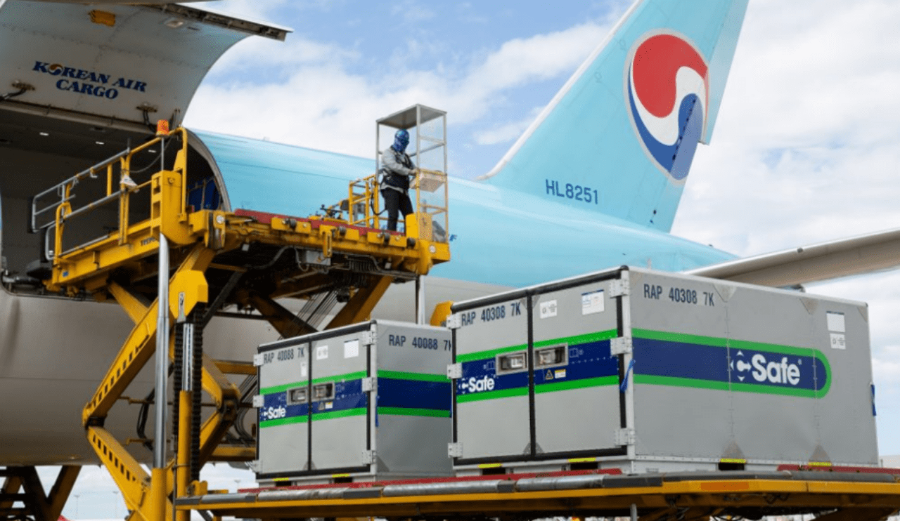 Korean Air Cargo aircraft (registration HL8251) being loaded with temperature-controlled freight containers branded e-Safe using a yellow hydraulic loader at an airport.
