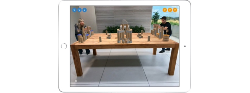 테이블을 사이에 놓고 남녀가 양쪽에서 ARKit이 탑재된 아이패드로 증강현실 게임을 즐기는 모습