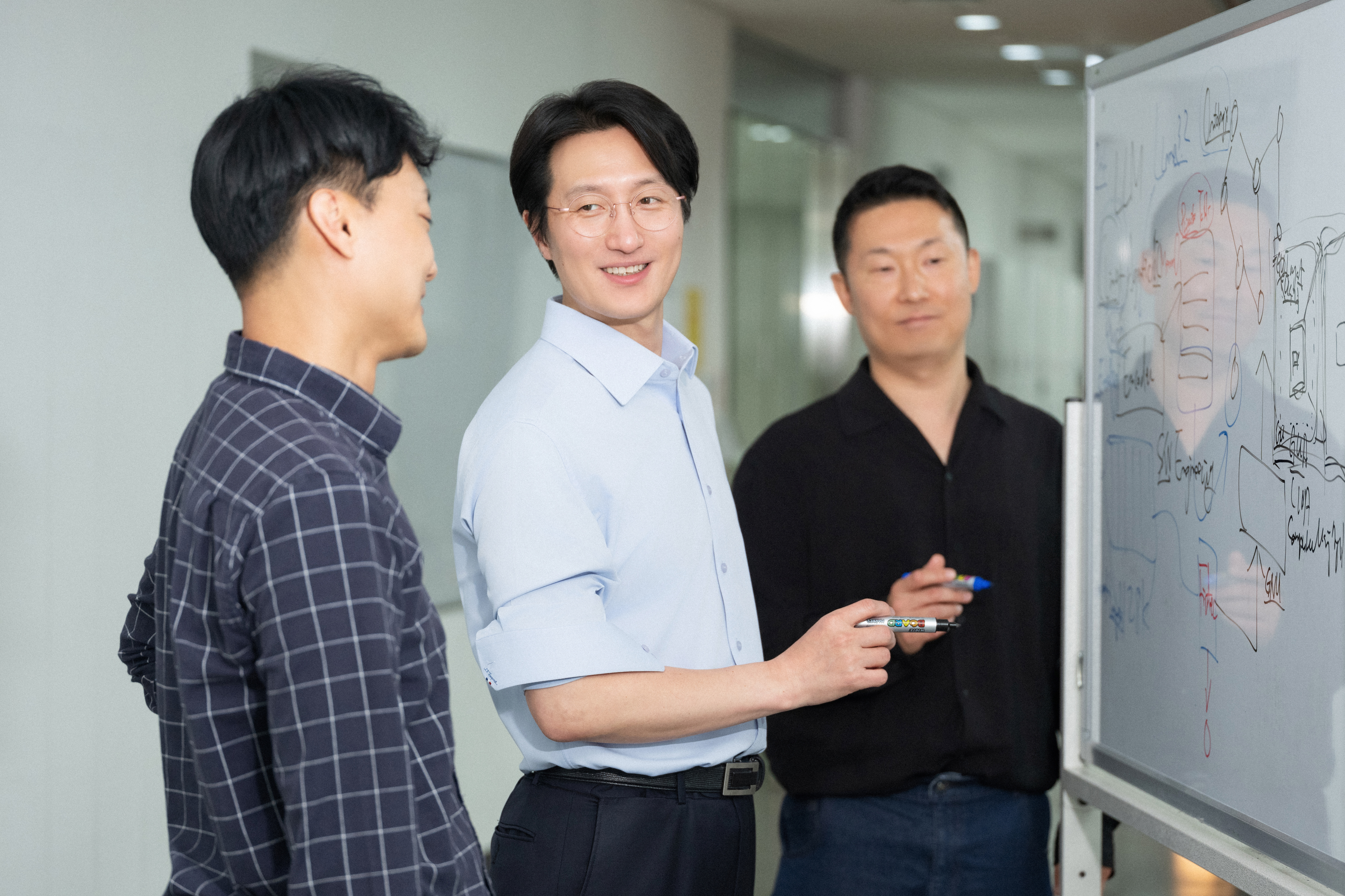 이태희 AI 연구팀장이 화이트보드 앞에서 랩장들과 함께 삼성SDS의 AI 기술에 대해 토론하고 있는 모습입니다. 
